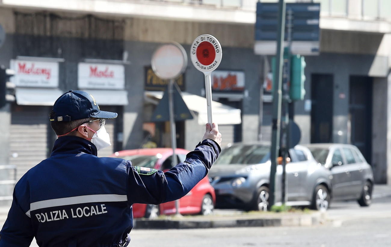 Un poliziotto della polizia locale ferma vetture che si spostano inutilmente.