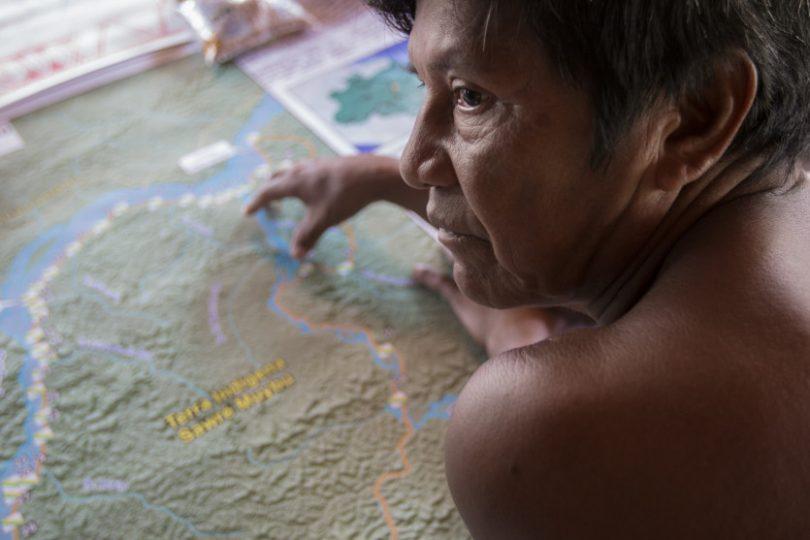 Indígena aponta para um mapa