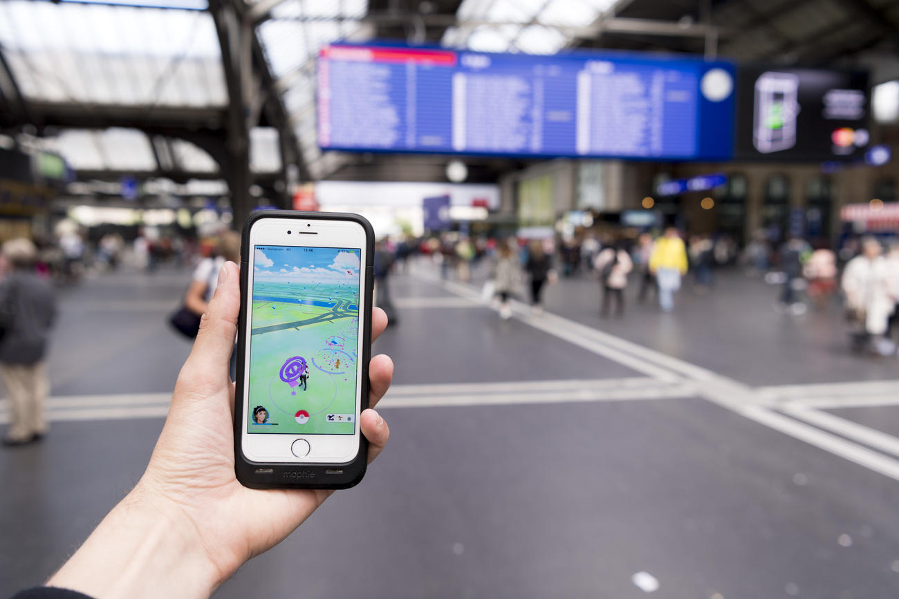 Celular em primeiro plano com estação de trens ao fundo