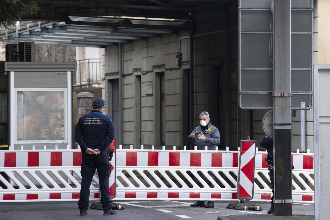 Alla dogana di Brusino Arsizio un doganiere svizzero parla da lontano a una guardia di finanza italiano: a dividerli una sbarra.