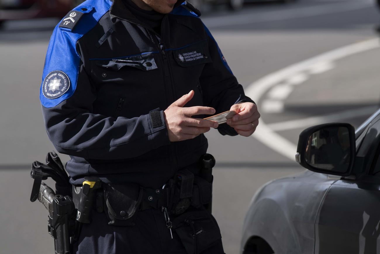 Primo piano a mezzo busto di una guardia di confine svizzera che controlla il documento di un automobilista