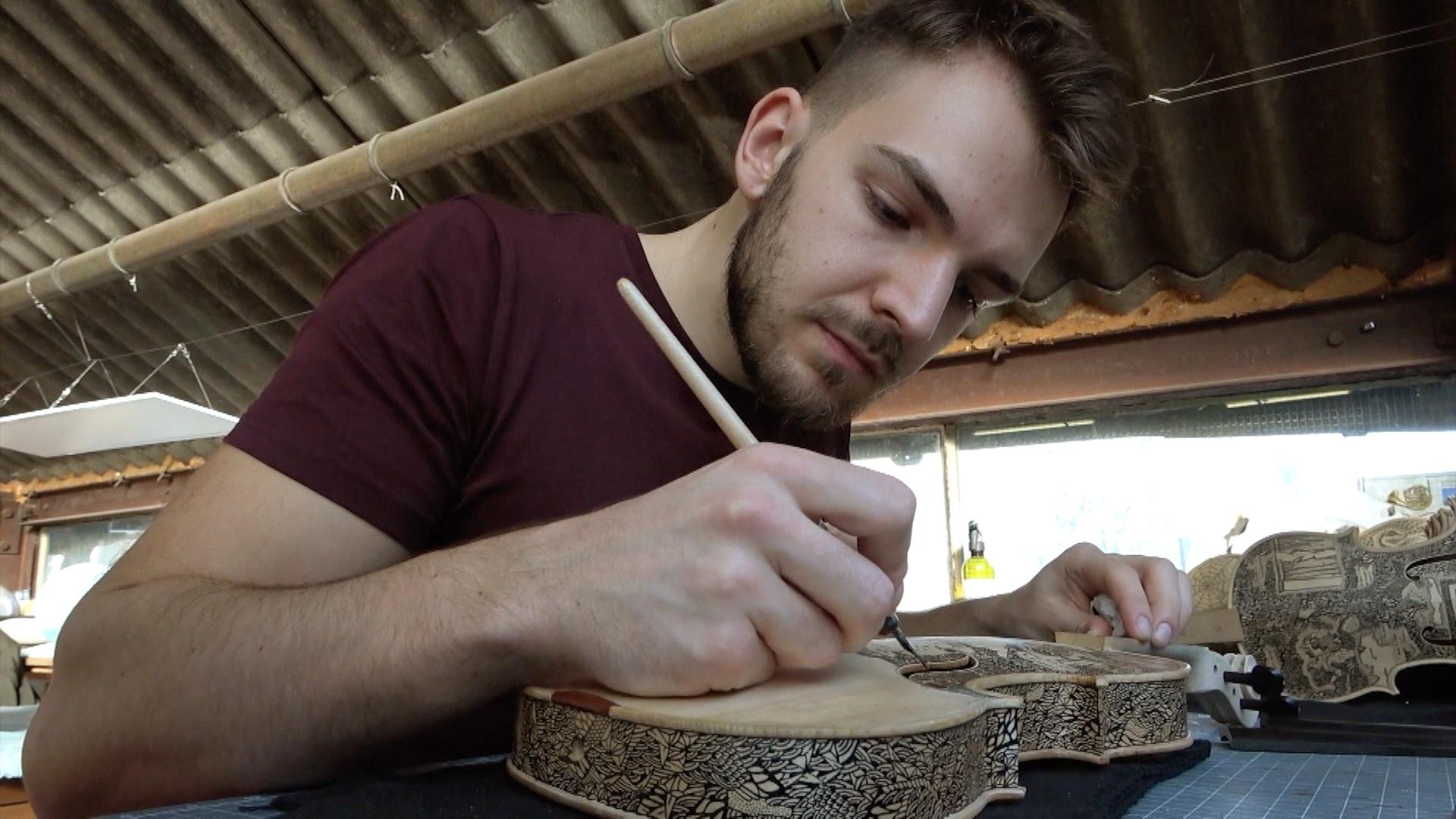 uomo disegna su un violino