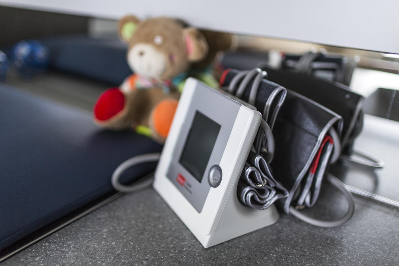 Apparecchio per misurare la pressione posato accanto a un orsetto di peluche in ambiente ospedaliero.