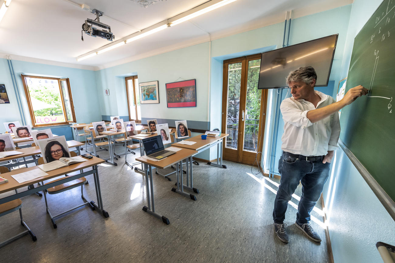 Un docente in un aula vuota collegato via computer con gli allievi a casa