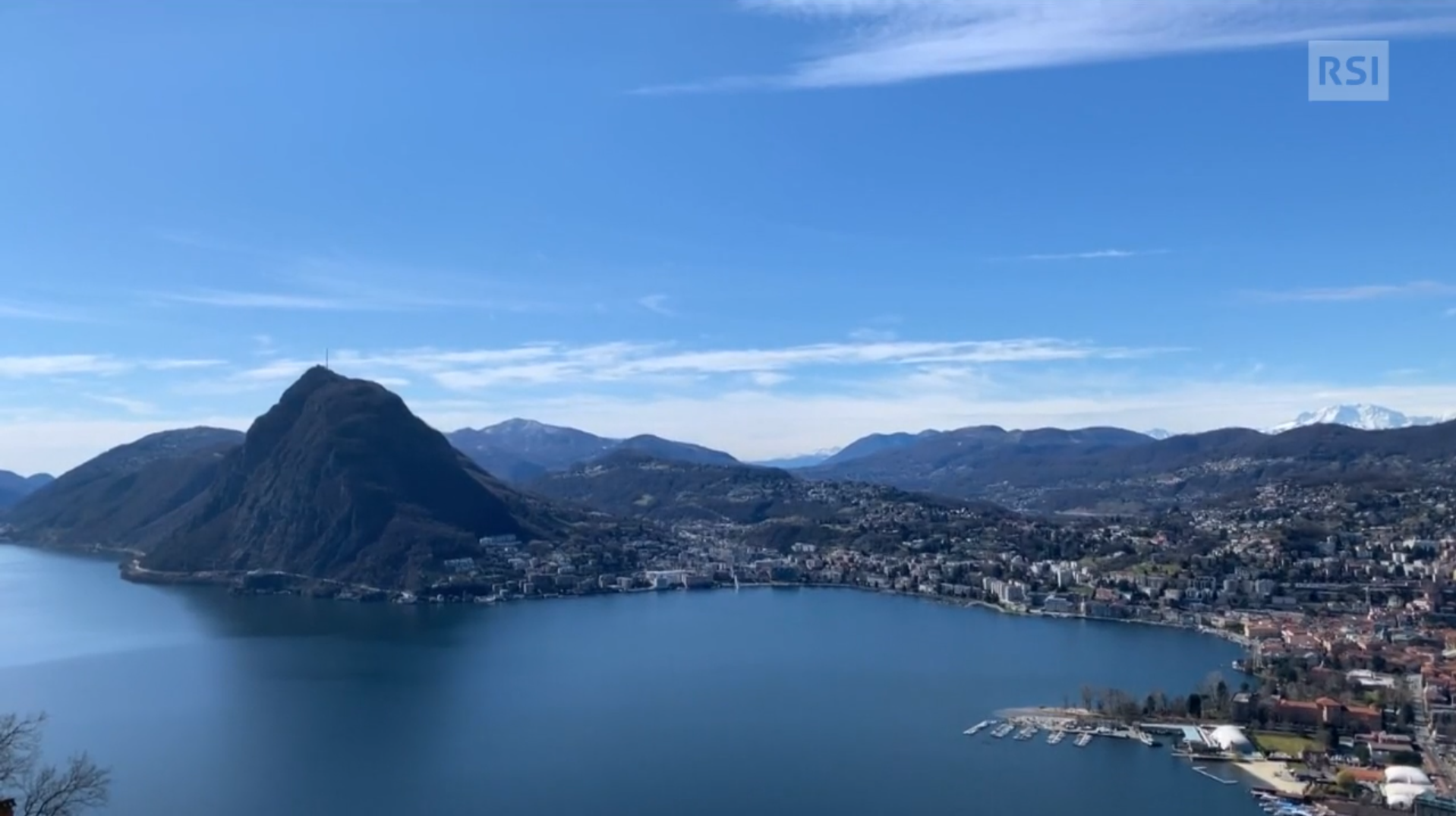 Veduta aerea non perpendicolare della baia di un lago, con monte appuntito e città su foce di fiume