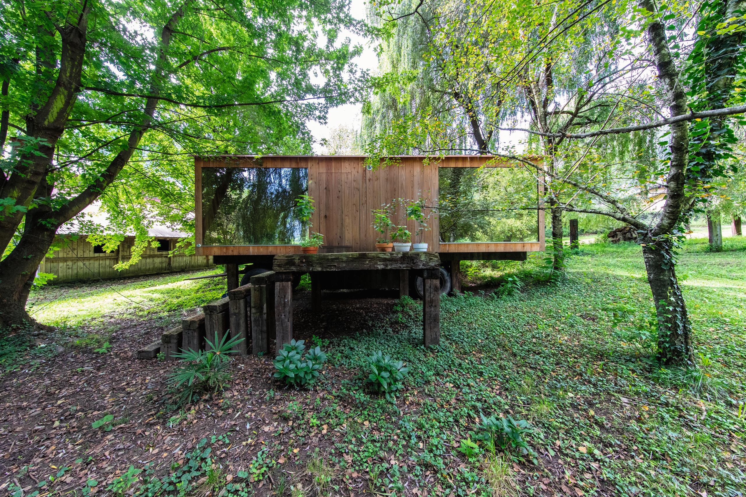 Petite maison en bois au milieu des arbres.