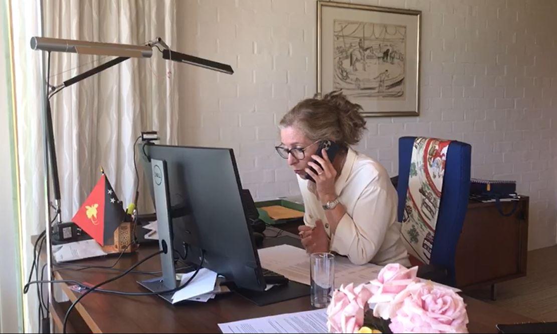 Una mujer sentada frente al ordenador y hablando por teléfono