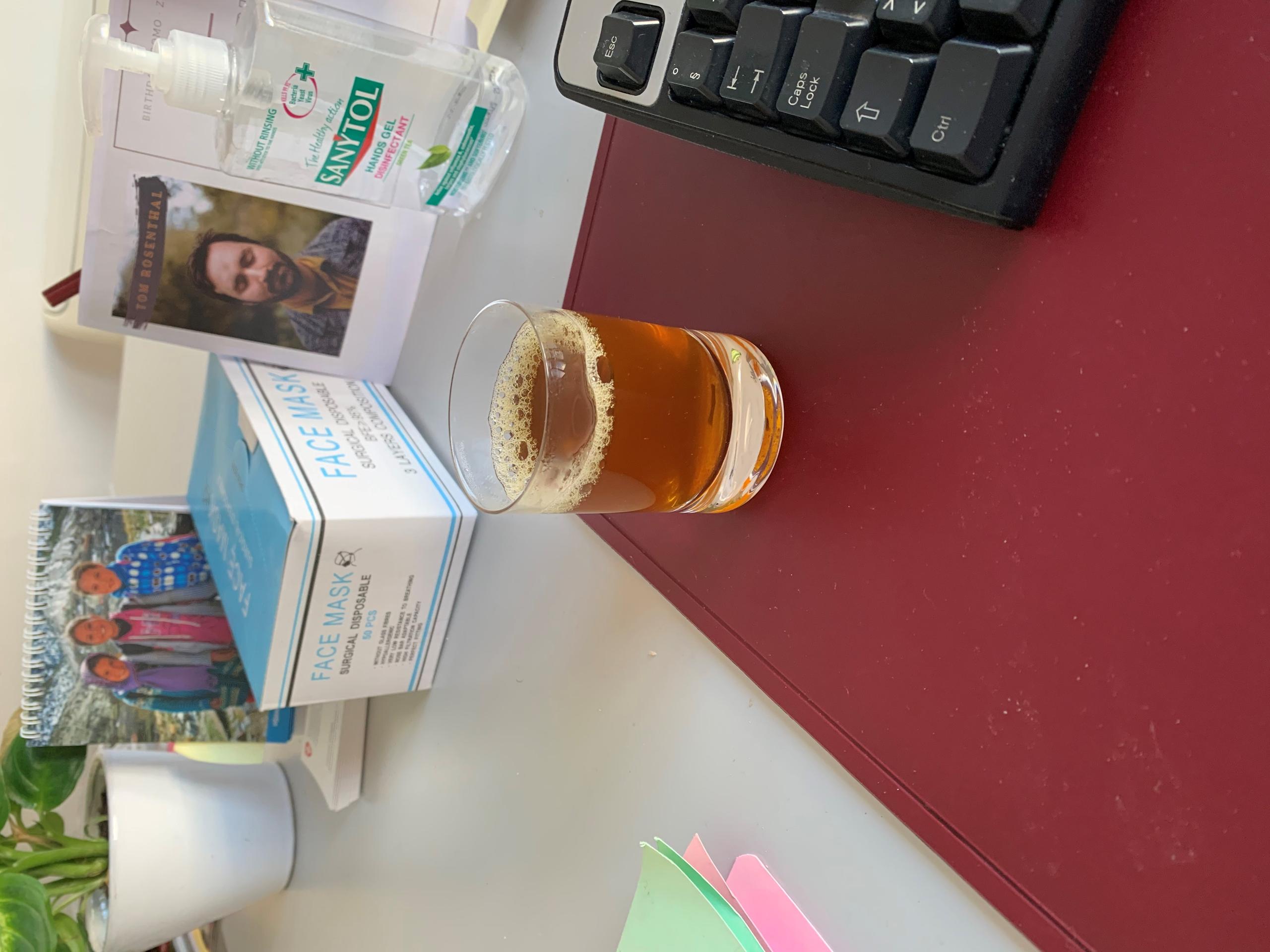 Una mesa de trabajo con un vaso de té marroquí y geles desinfectantes