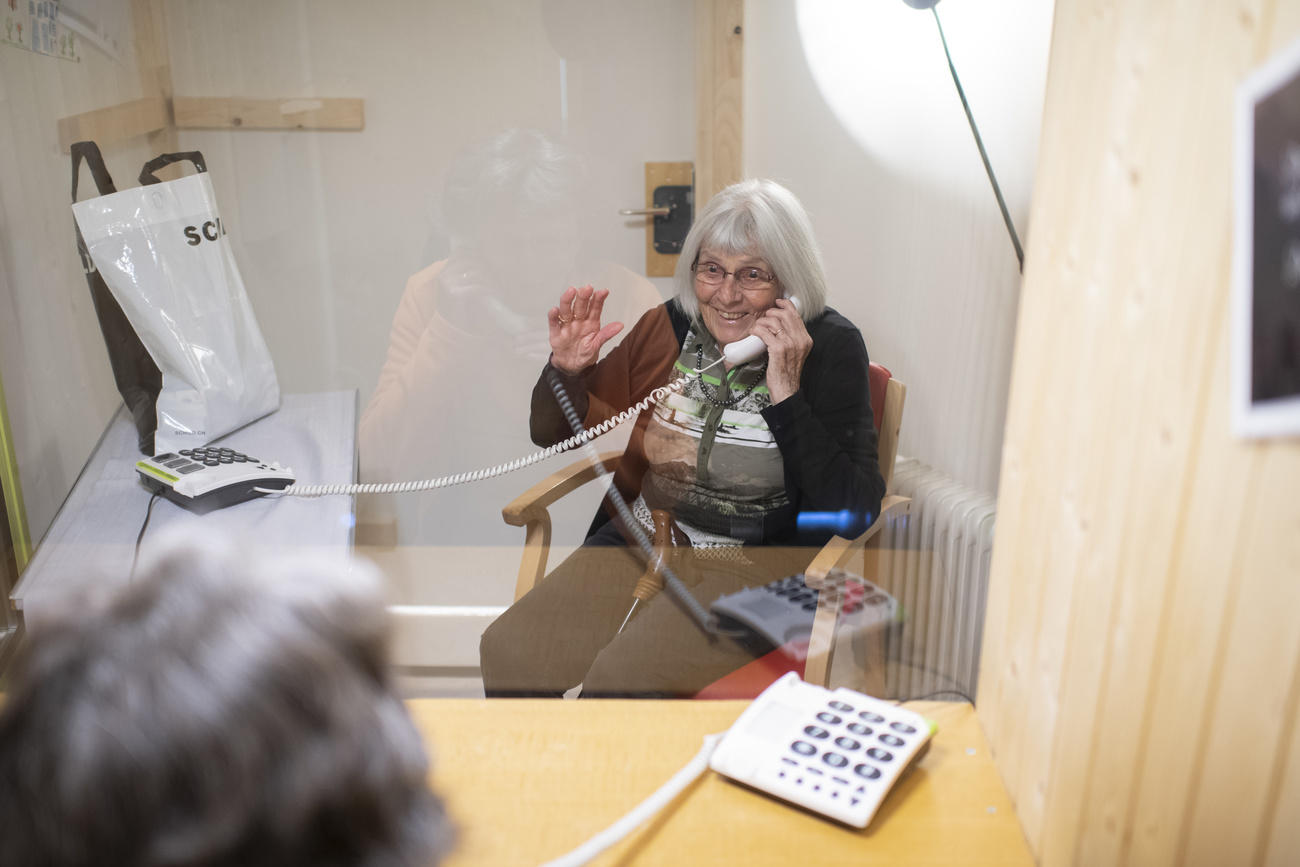 Elderly woman using a phone to talk to a visitor