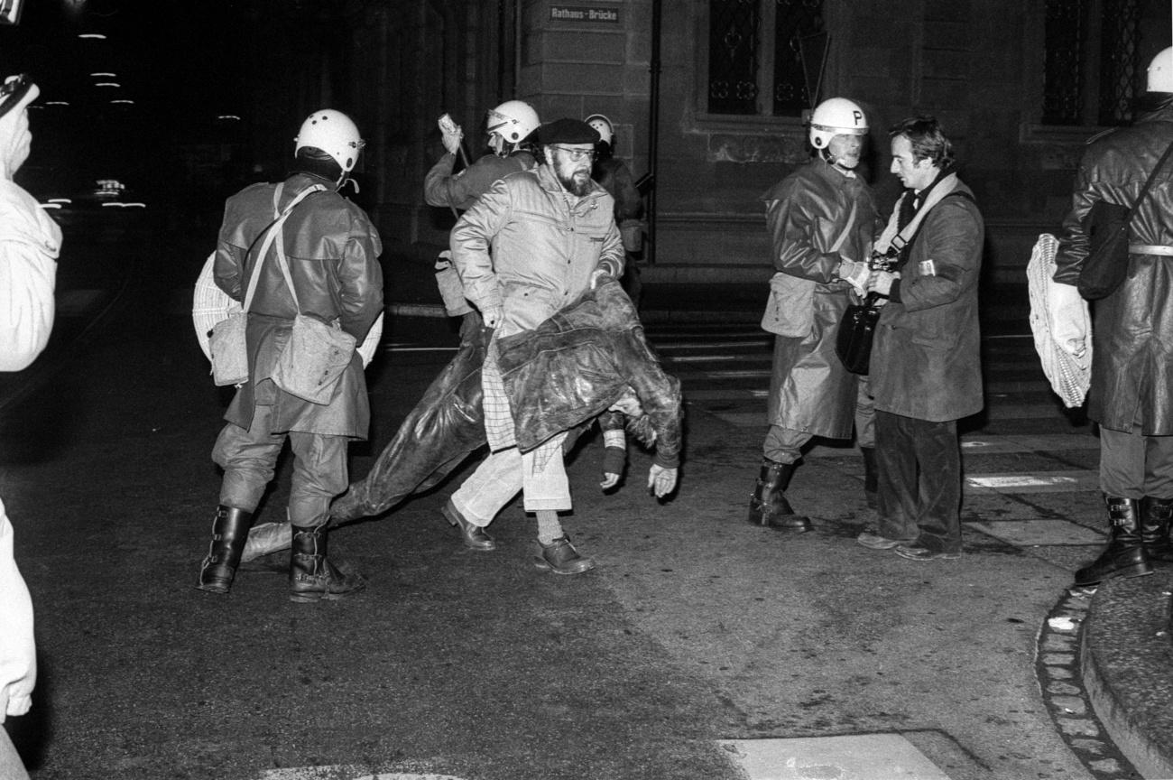 Un manifestante herido es llevado por un policía de civil.