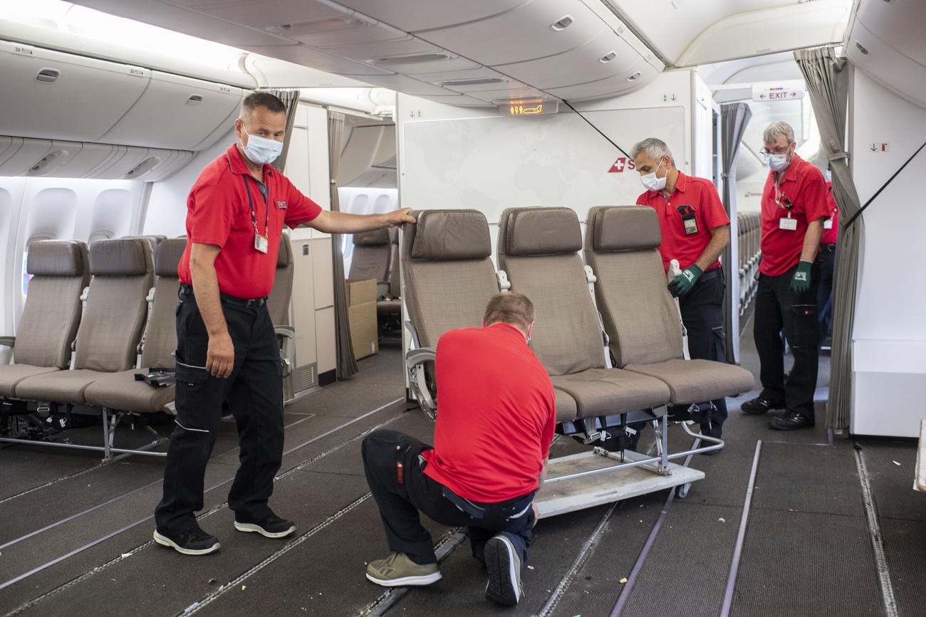 quattro persone smontano una fila di sedili su un aeroplano