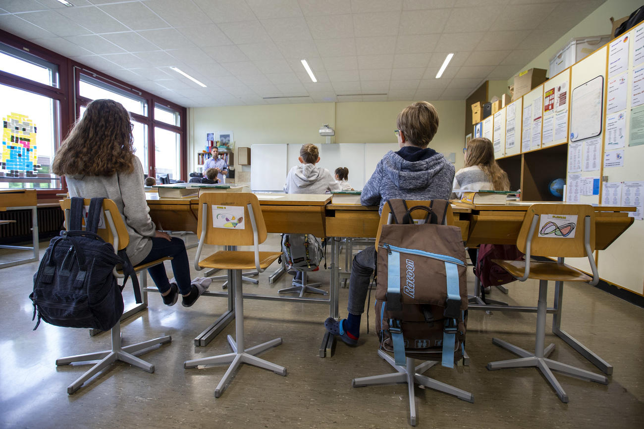 Sylvain, teacher, talks to half of his pupils in a classroom at a primary school, in Lully near Geneva
