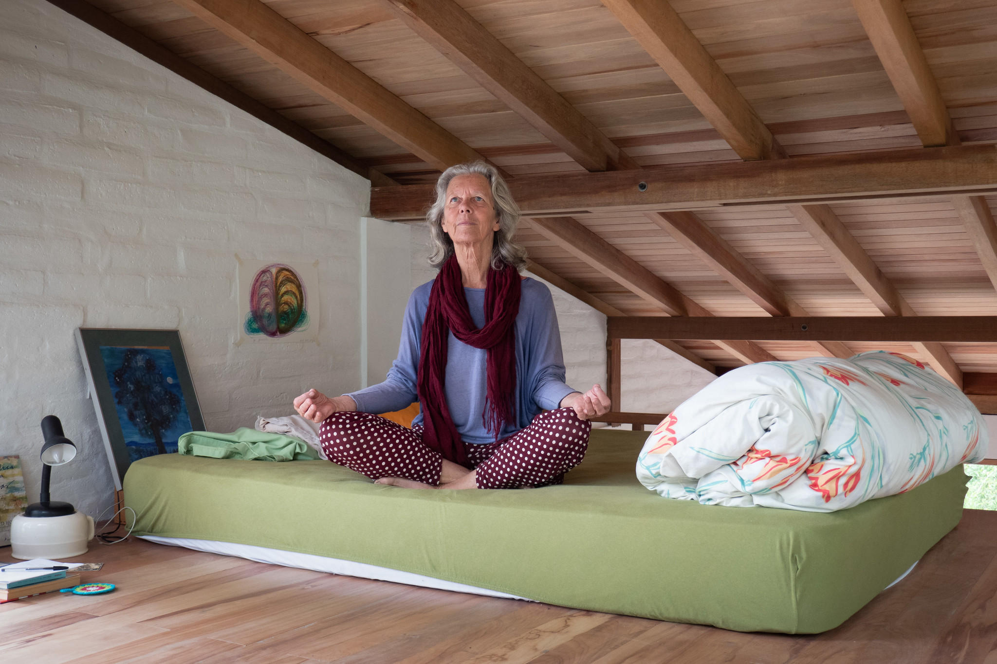 Eine Frau sitzt auf einem Bett und meditiert.