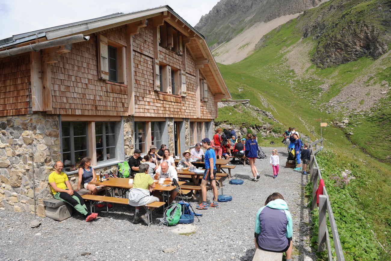 Eine besetzte Terrasse vor einer Hütte in den Bergen.