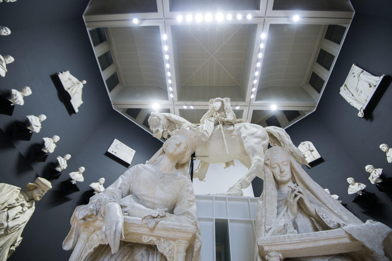 Una sala con pareti grigio scuro e colma di sculture vista dal basso