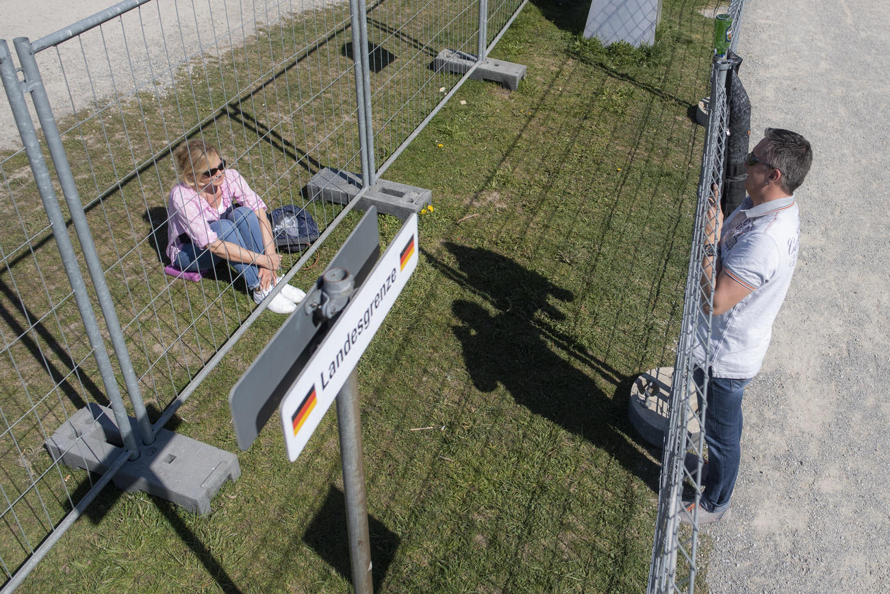 people meeting, separated by border fence