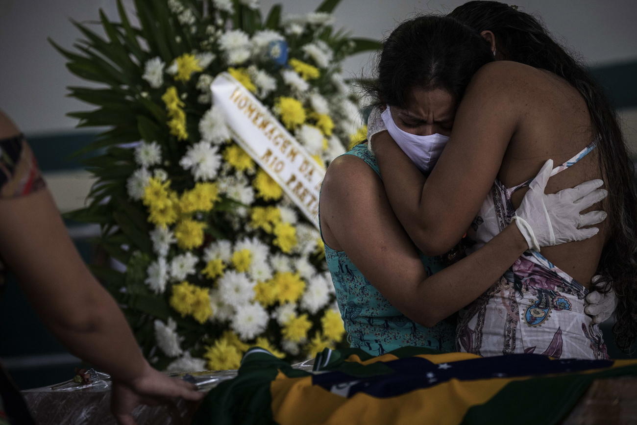 Dos mujeres lloran y se abrazan durante un funeral