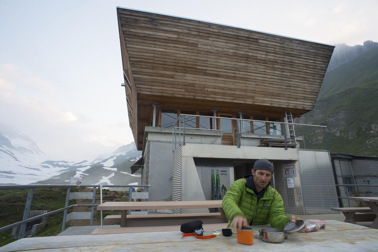 Ein Mann sitzt an einem Tisch vor einer Hütte.