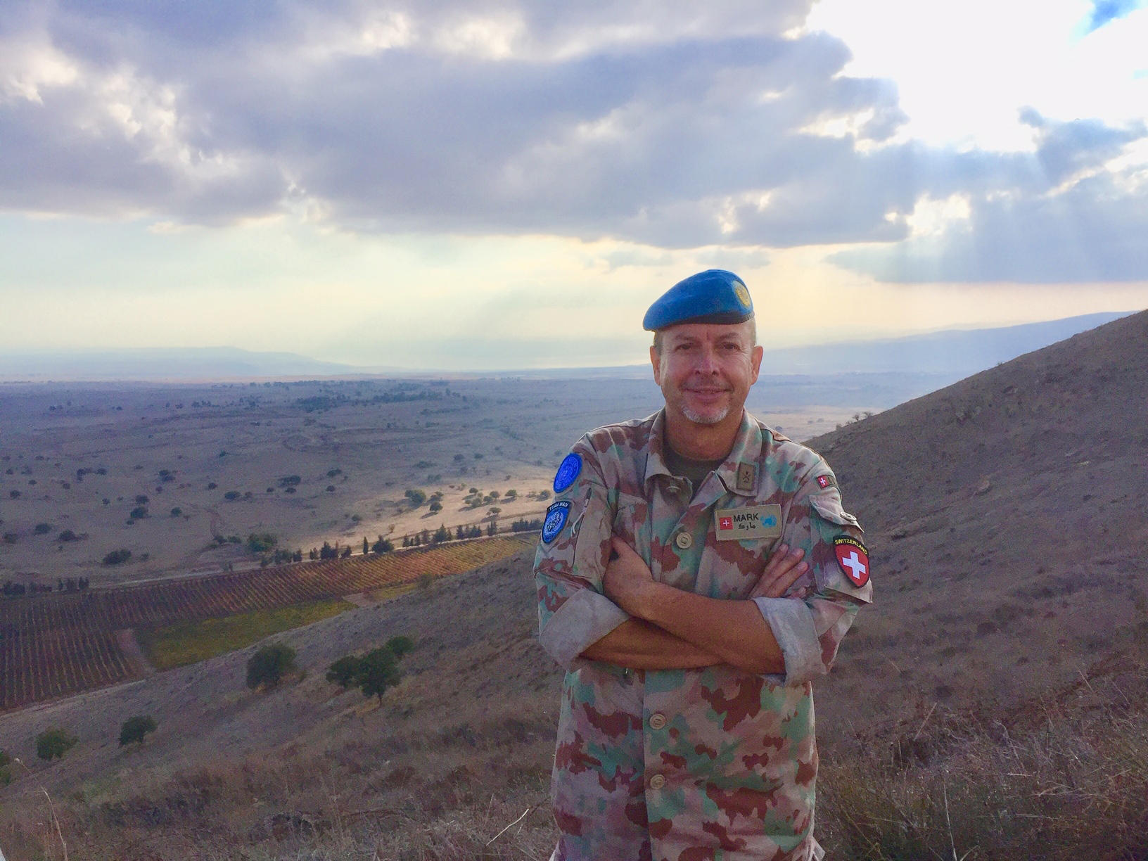 Ein Mann in Uniform steht vor einer kargen Landschaft.