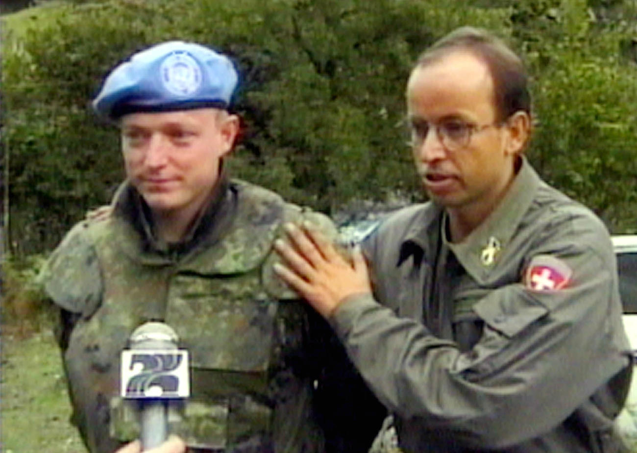 Zwei Männer in Uniform stehen vor einem Mikrofon.