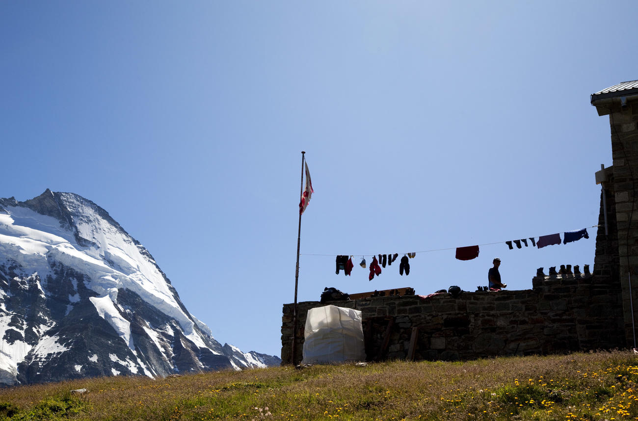 Blick auf eine Berghütte, im Hintergrund ein verschneiter Berg.