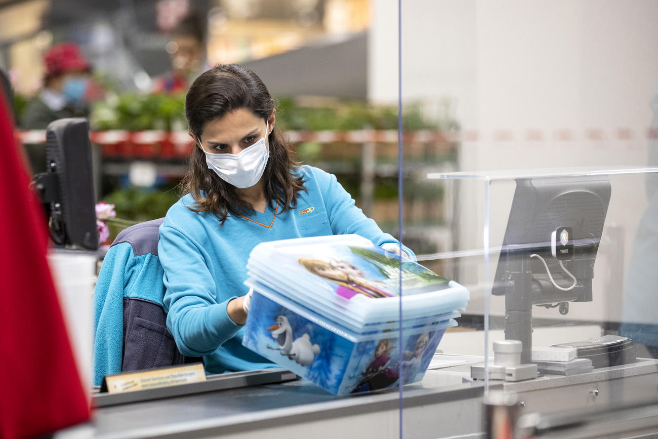 Una cassiera con la mascherina al lavoro