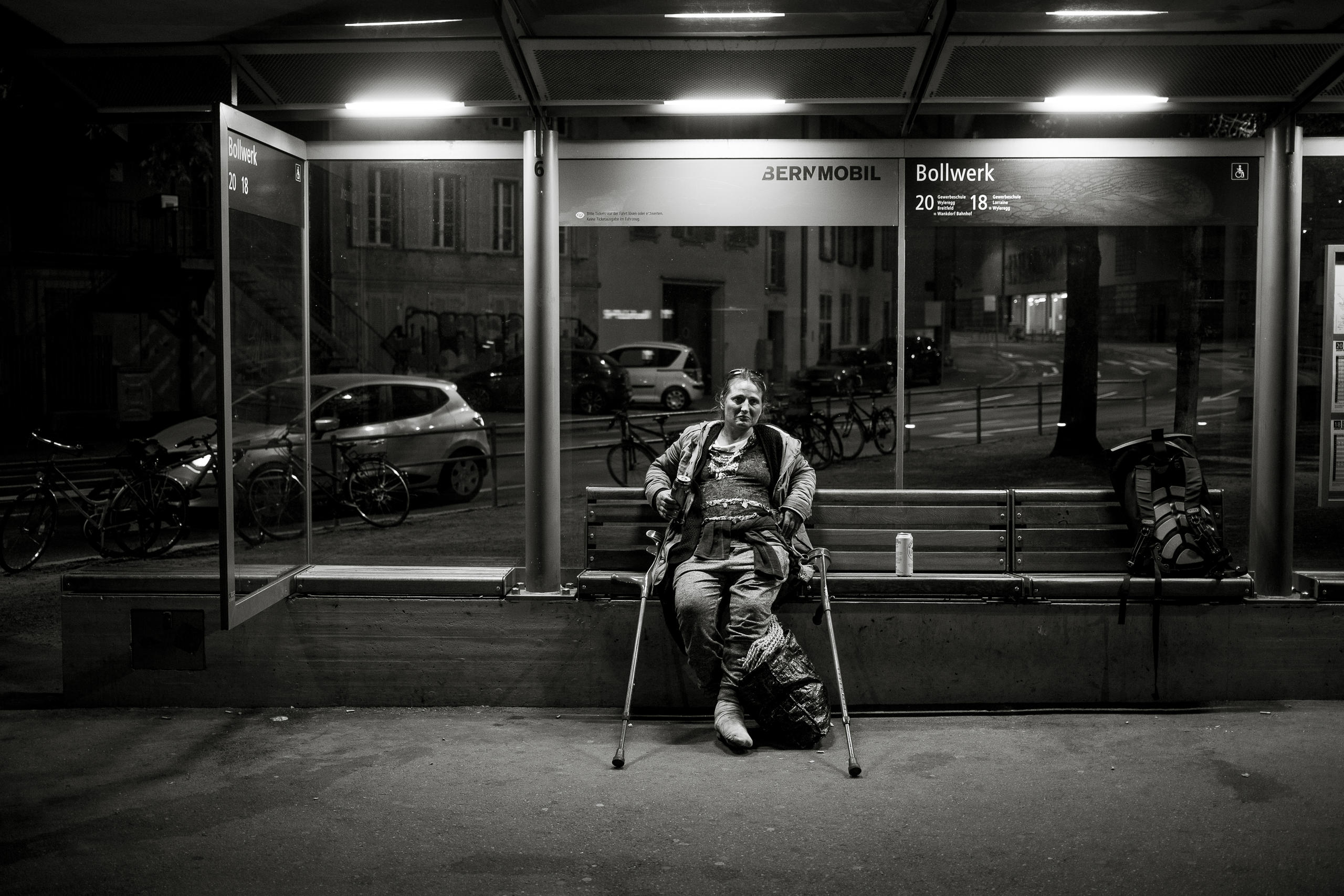 une femme assise sur un banc à un arrêt de bus