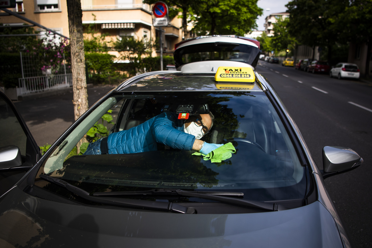 A taxi driver cleaning his windscreen.