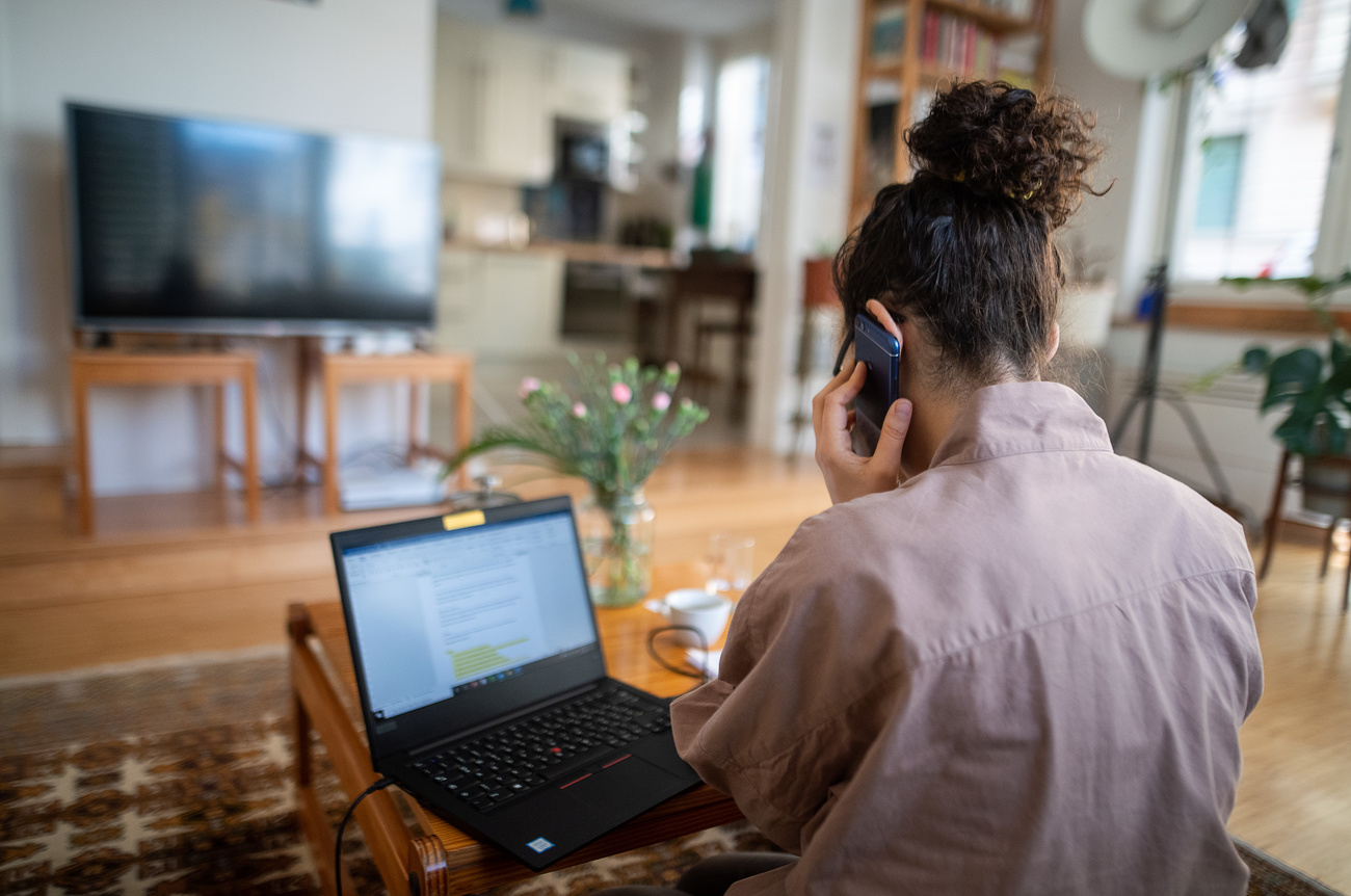 Une employée au téléphone et devant son ordi dans son salon