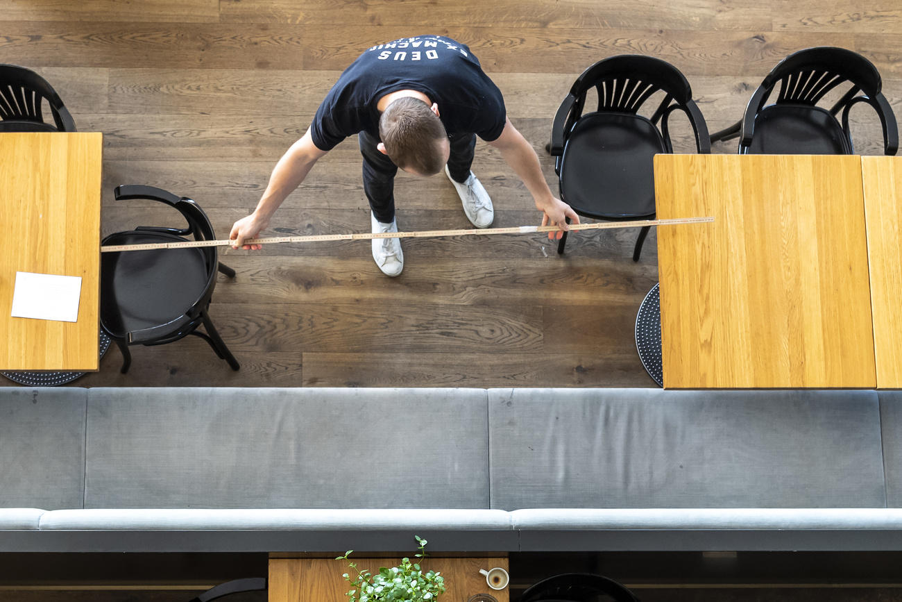 Man with measuring tape between tables