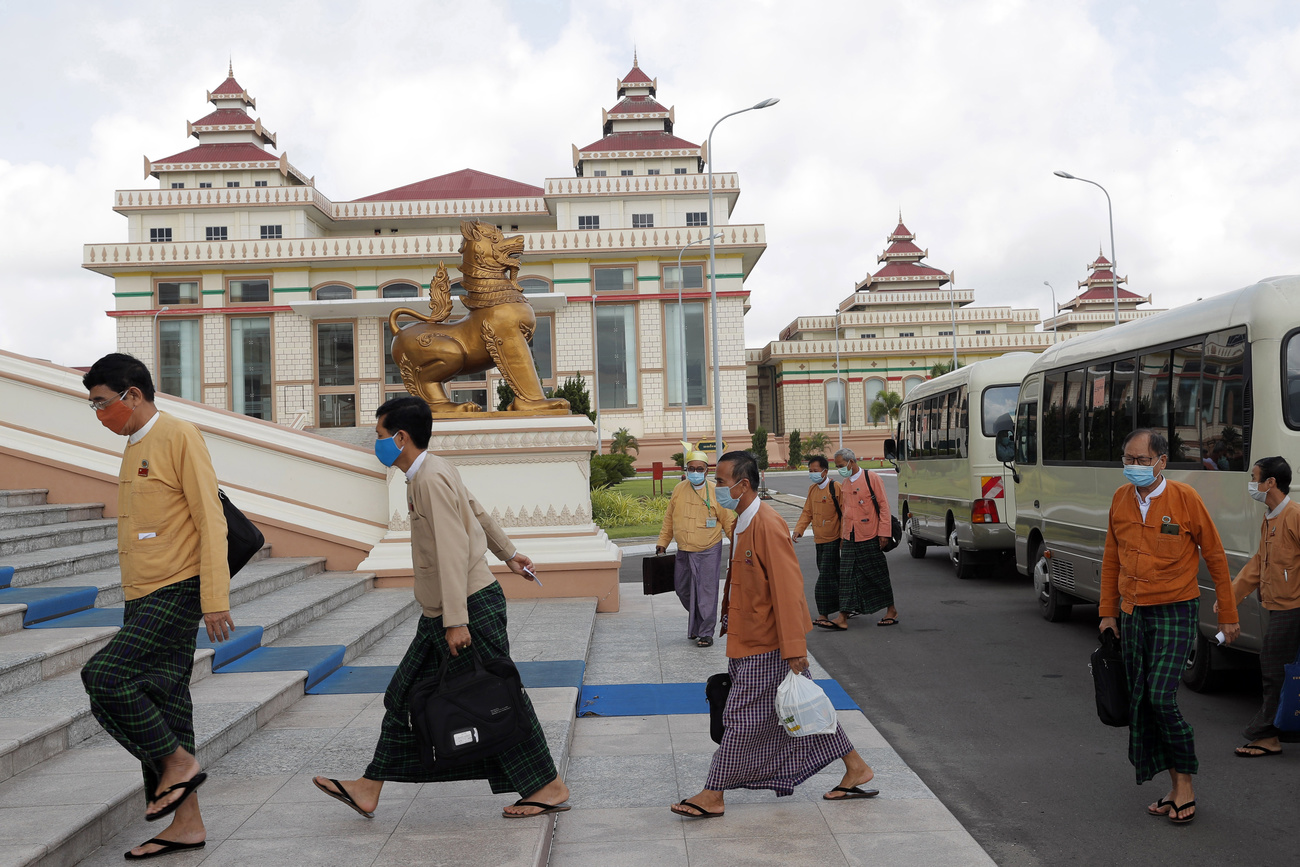 People in face masks walking from buses to a building