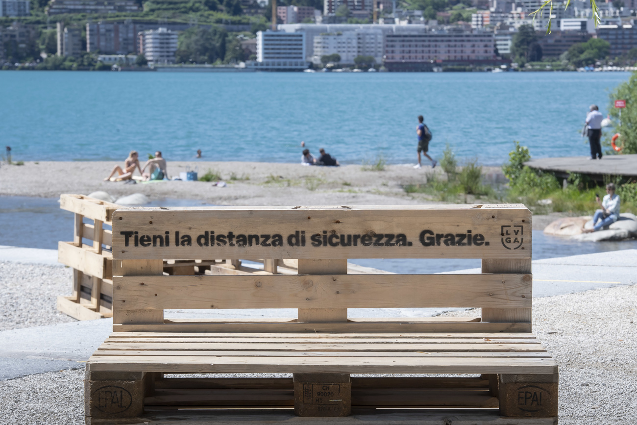 Una panchina a bordo lago con scritto Tieni le distante di sicurezza, grazie.