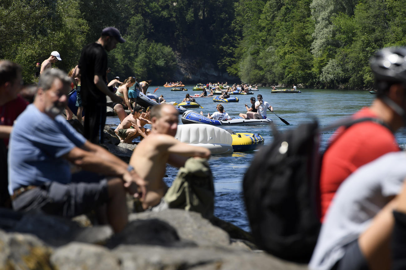 gente in riva a un fiume e persone a bordo di canotti gonfiabili