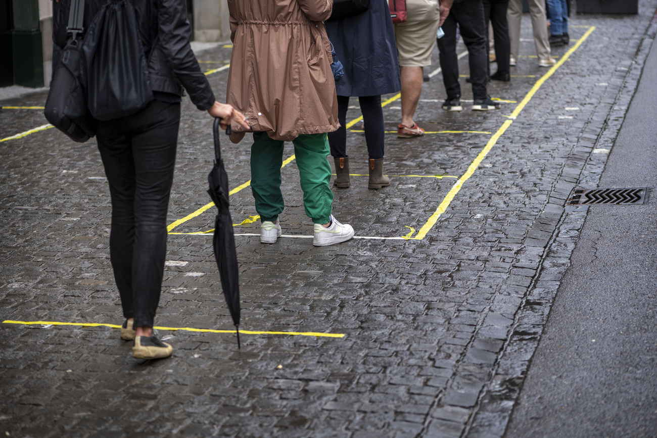 Fila de personas con distancia marcada en el suelo