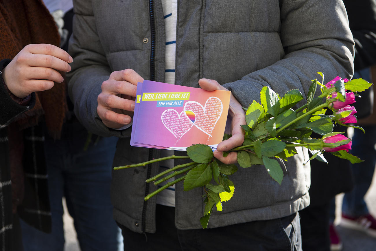 Two men with wedding card and bunch of roses