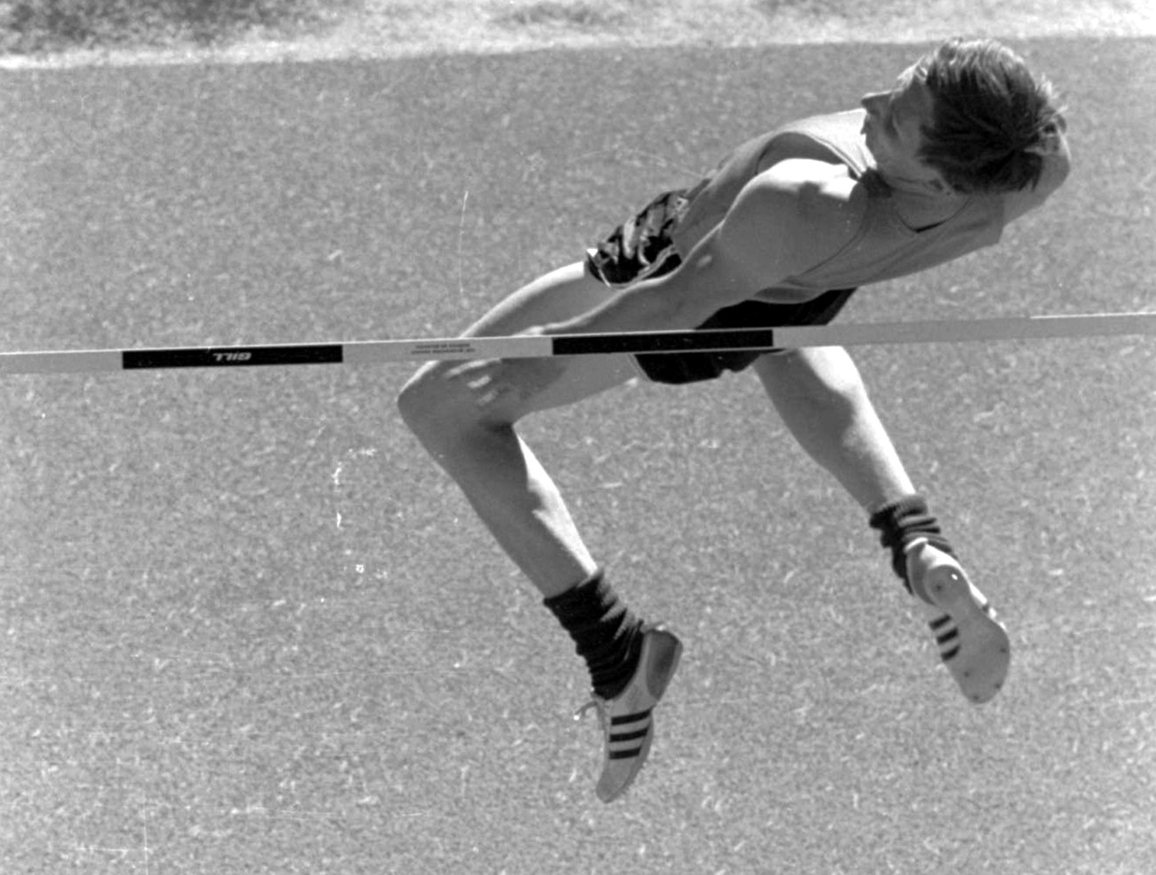 Atleta uomo nel momento in cui supera l asta, di schiena, in una prova di salto in alto.