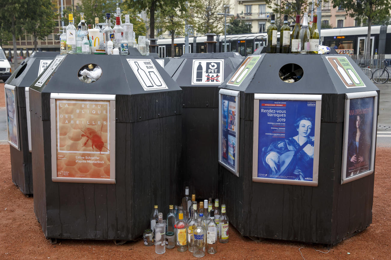 Botellas y otra basura sobre los contenedores