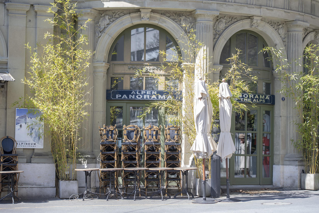 Un ristorante chiuso, con ombrelloni, sedie e tavolini impilati uno sopra l altro.