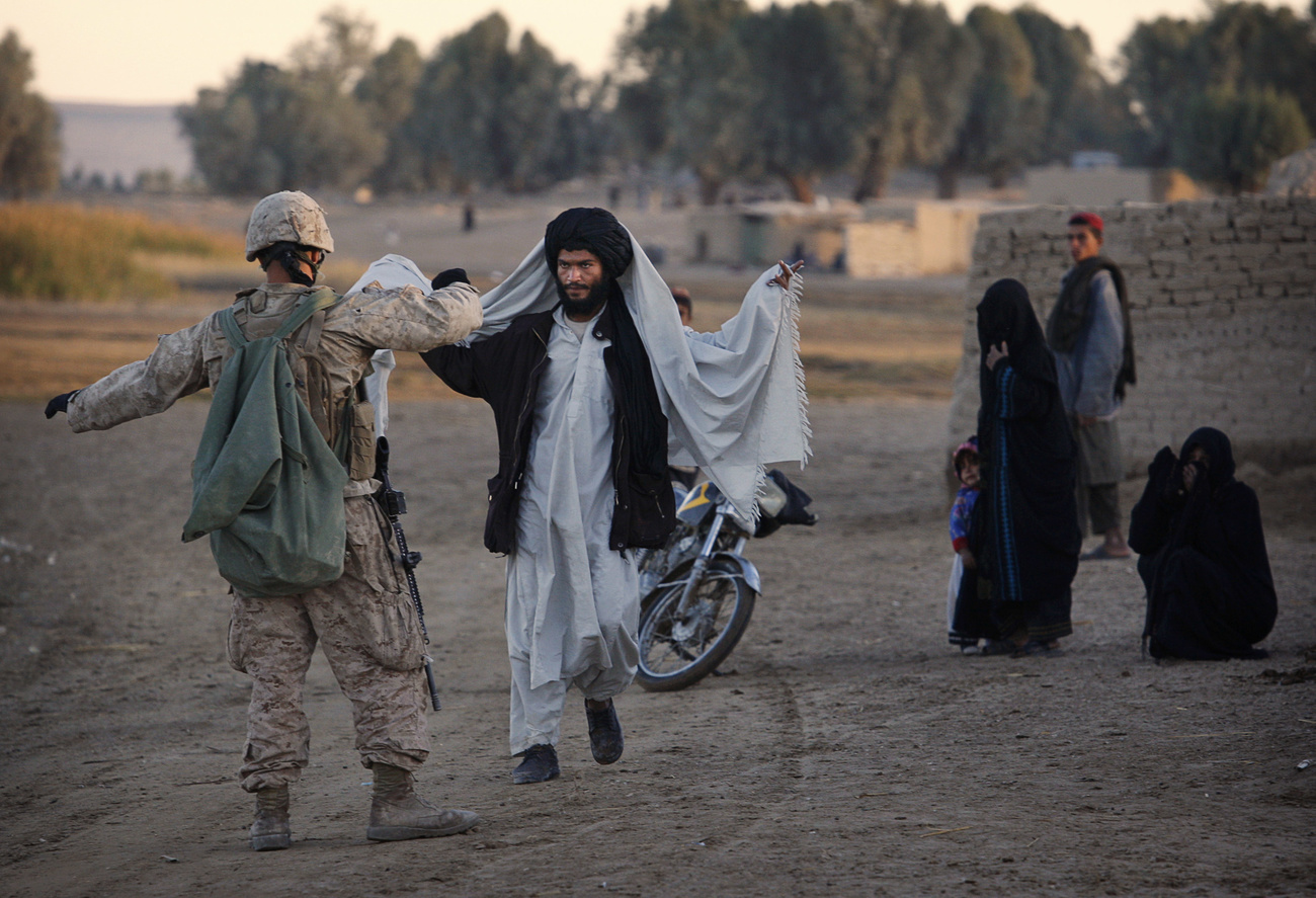A US marine searches an Afghan man in Helmand Province (2009).
