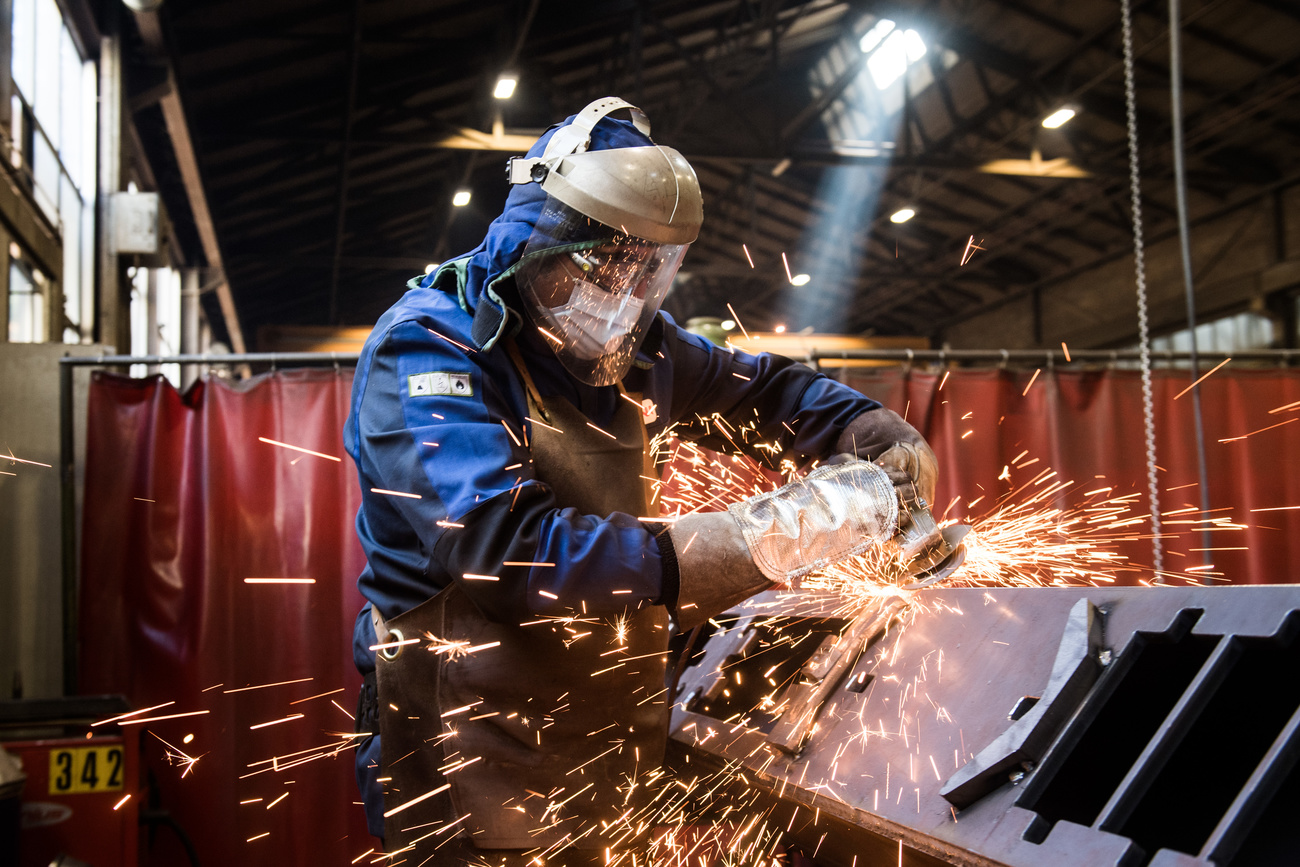 Un metalmeccanico al lavoro con le normali protezioni e con la mascherina.