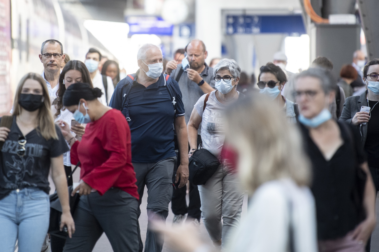 Grupo de personas con mascarillas protectora en estación de trenes de Zúrich.