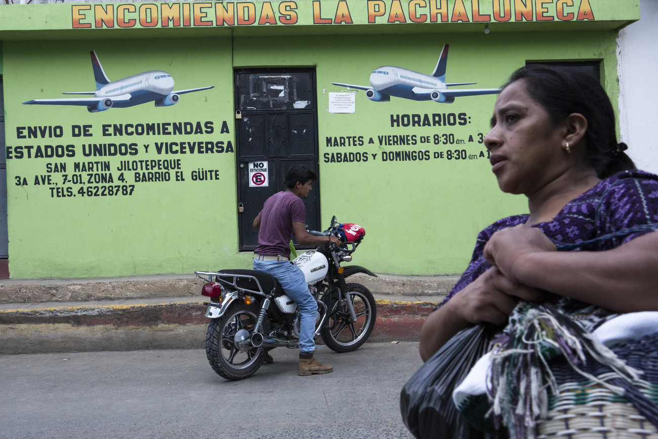 Un motorista y una mujer pasan delante de un local de envío de remesas