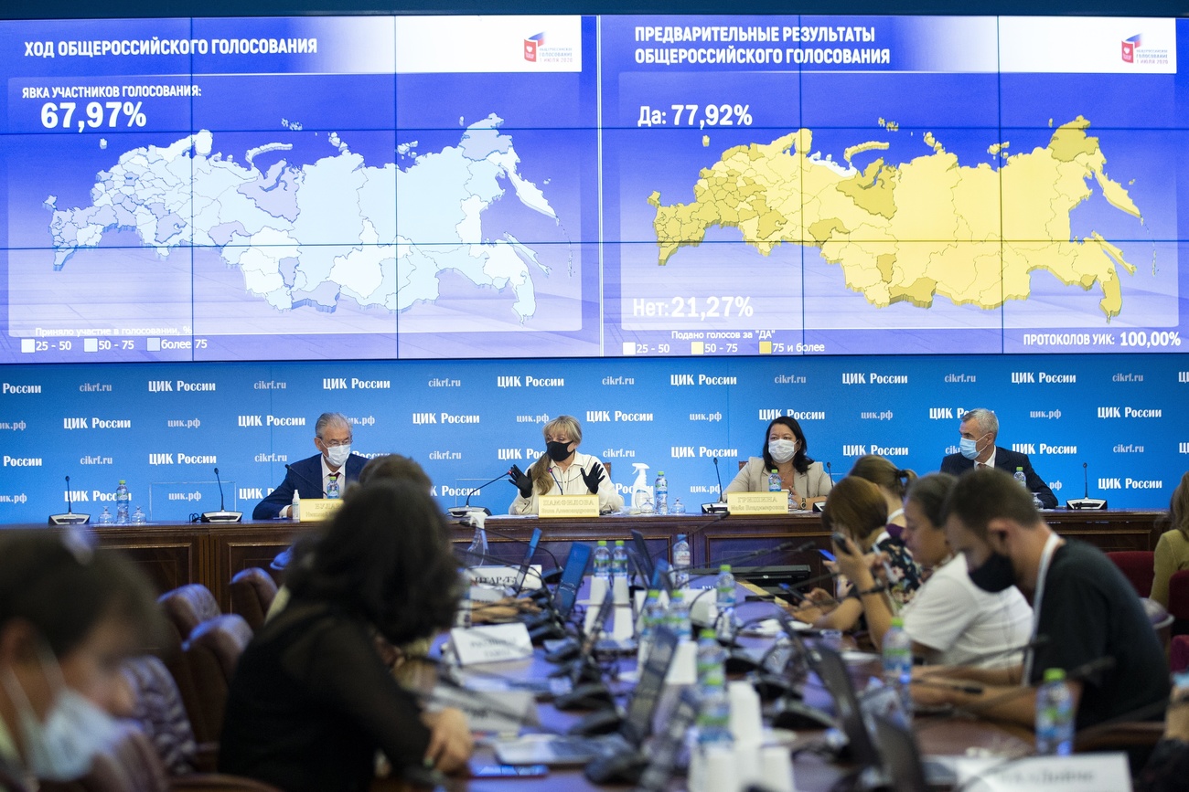 Sala con delegati o forse giornalisti seduti lungo lunghi tavoli e maxischermo con cartina russa e risultati elettorali.