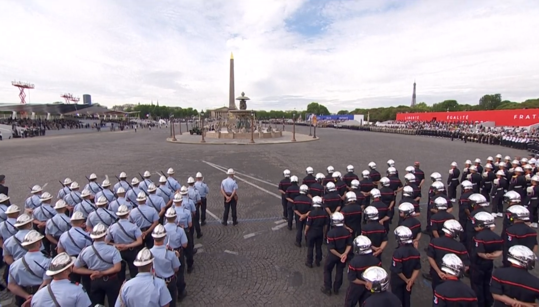 Piazza con obelisco, tutt attorno formazioni militari in rango.