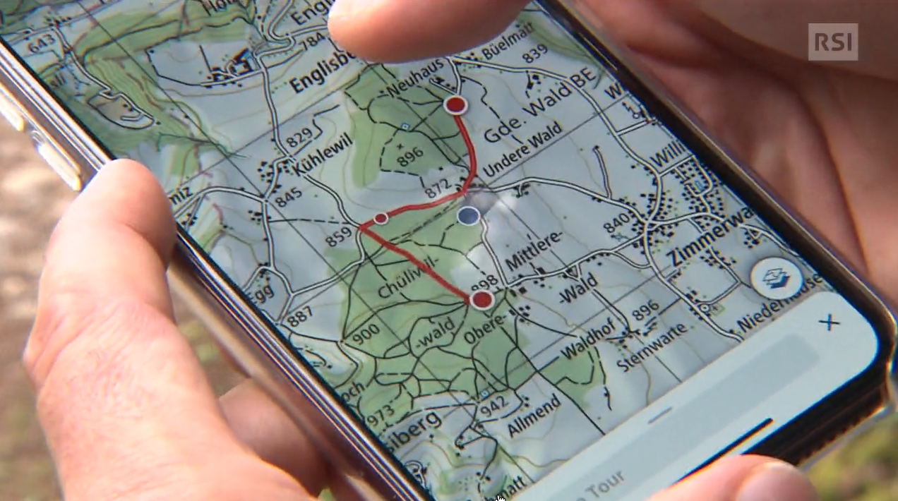 Primo piano di smartphone con applicazione di mappe/cartine, due dita tracciano un sentiero