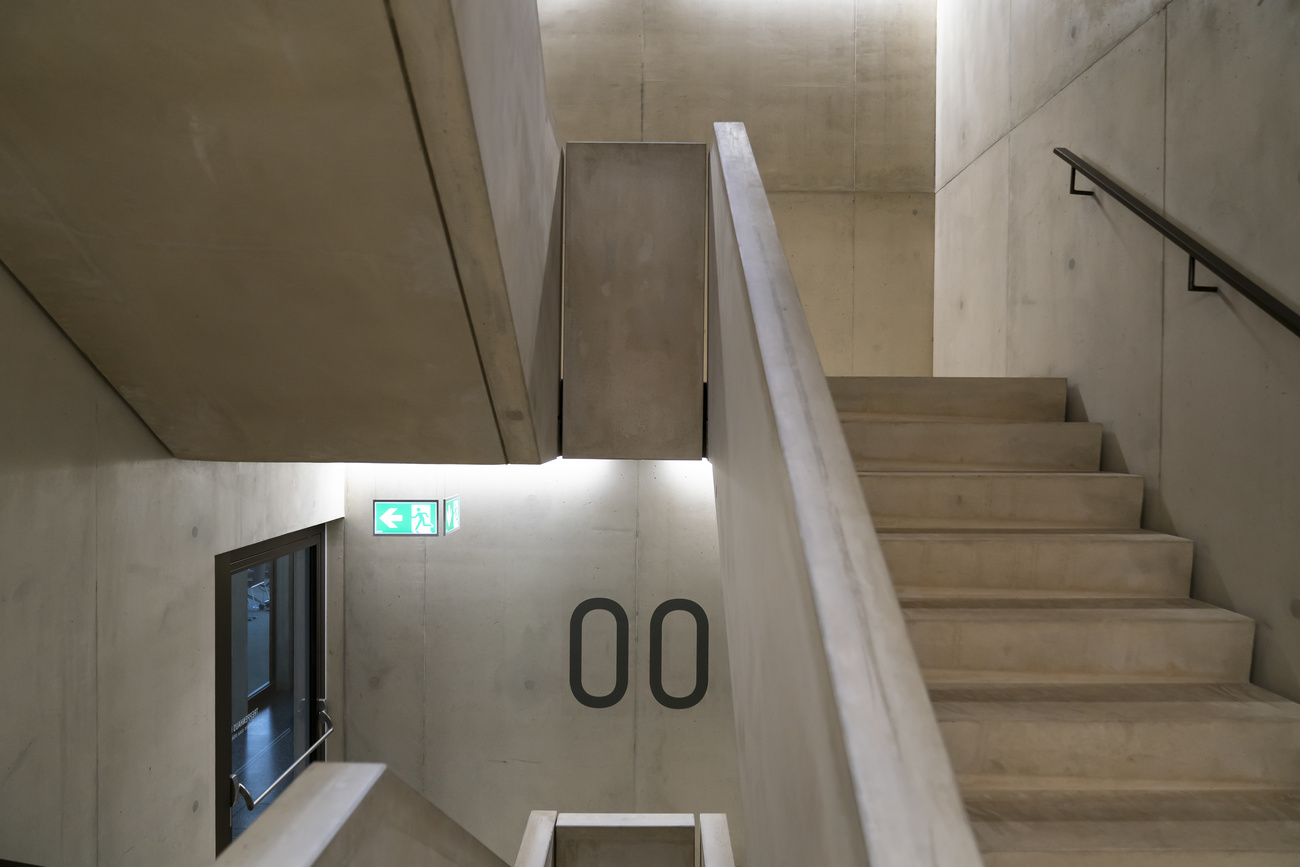 Scala interna di edificio brutalista ripresa da un mezzanino; si vede l entrata al piano 00