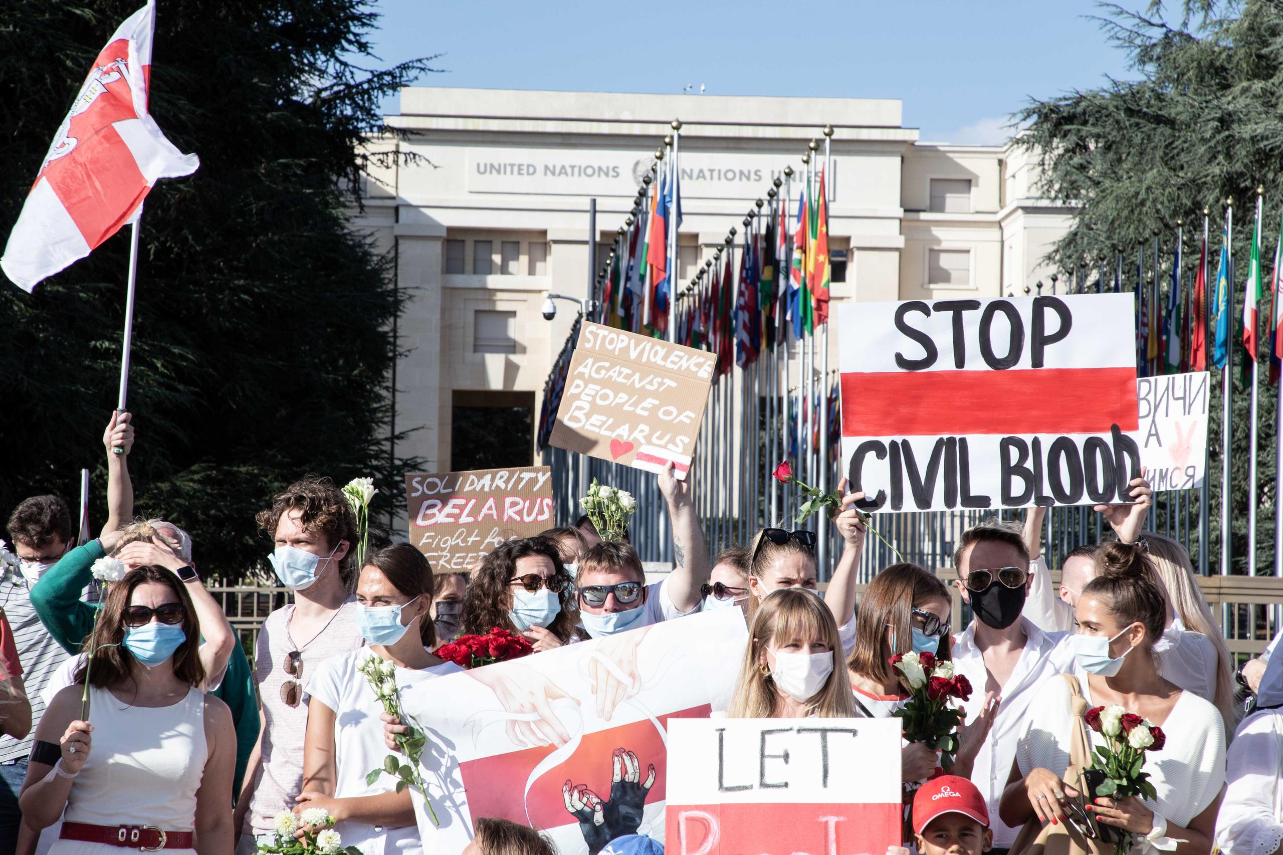 группа людей с плакатами перед зданием ООН