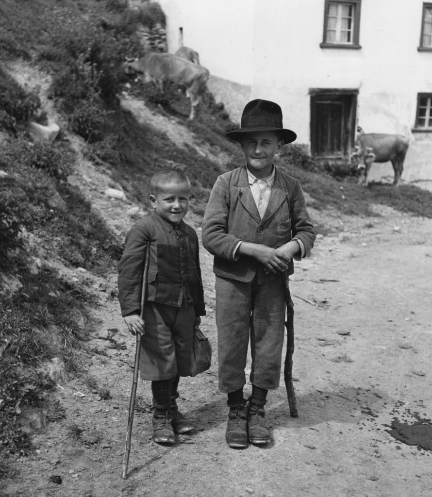 Deux enfants devant une maison et des vaches