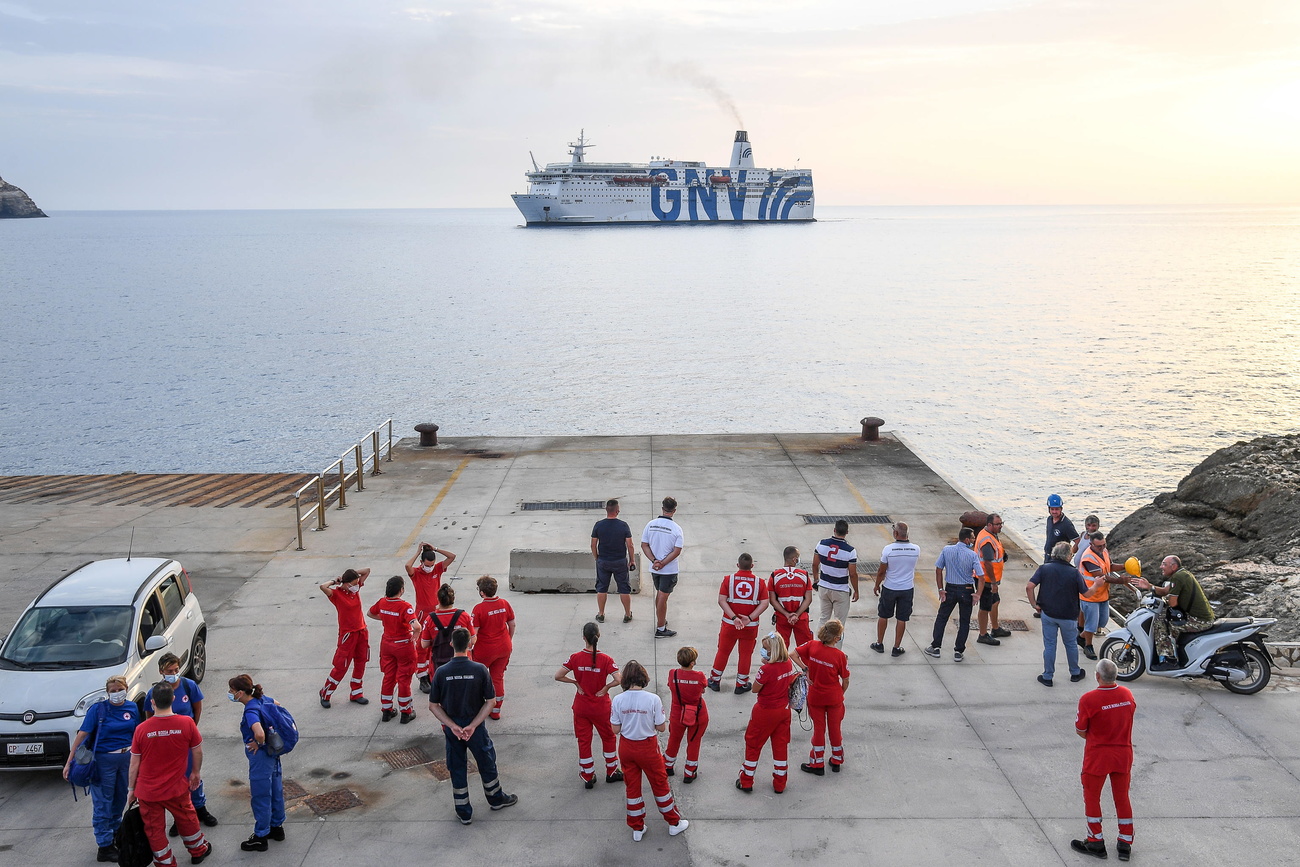 Nave con grande scritta GNV a babordo al largo di una banchina con personale sanitario