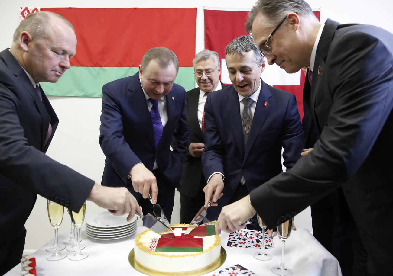 Männer schneiden Kuchen mit Schweizer und weissrussischen Flagge an